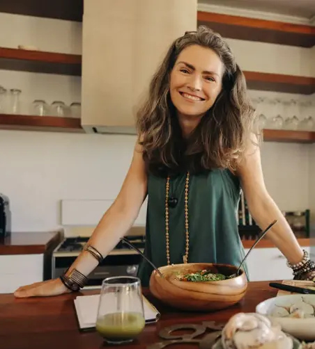 Middle-aged woman smiling while cooking in a cozy kitchen